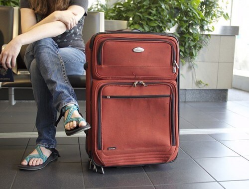 kobieta siedząca z walizką na lotnisku