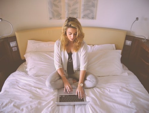 dziewczyna w łóżku pisze na laptopie